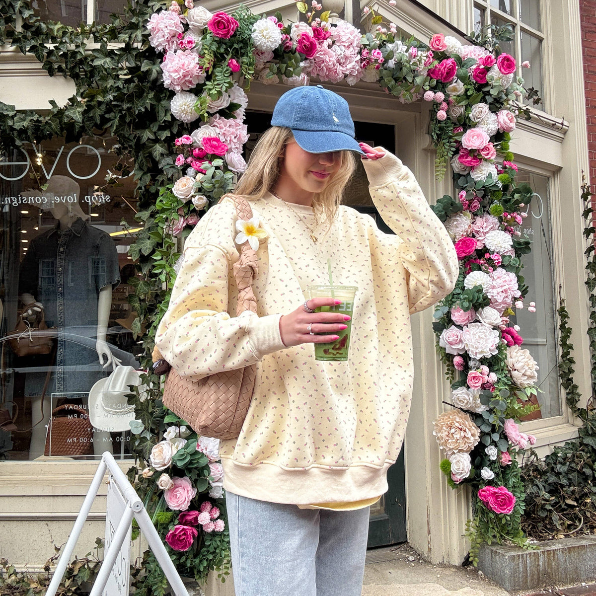 Person holding a drink in front of a decorated building with flowers