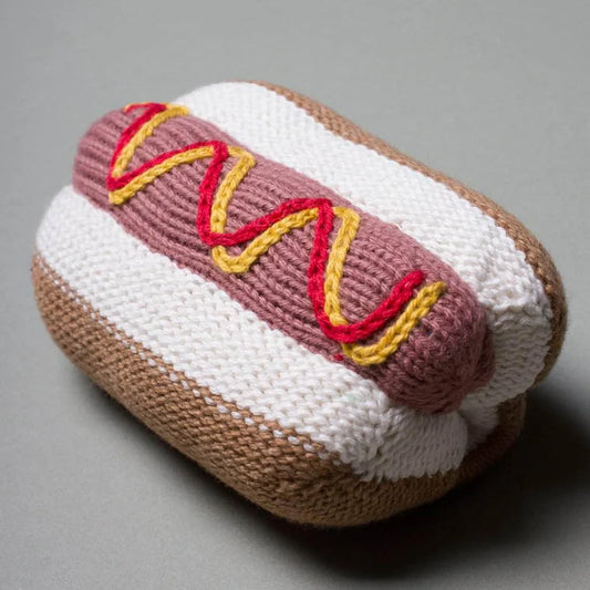 Knitted hot dog toy with mustard on a gray background