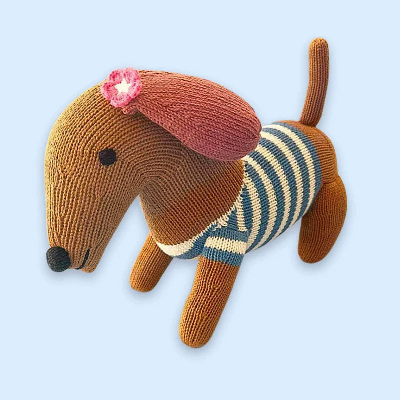Knitted dog toy with a striped sweater and pink flower on a light blue background